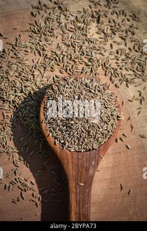 Graines de cumin en cuillère en bois sur fond en bois Banque D'Images
