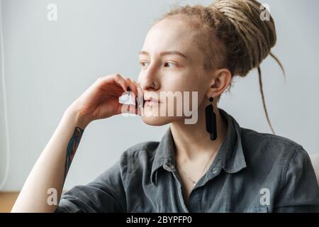 Image d'une jeune fille incroyable et relaxante avec des dreadlocks posant à l'intérieur. Banque D'Images