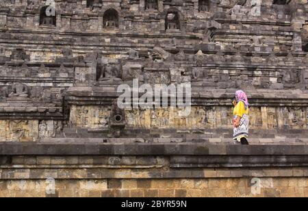 BOROBUDUR, INDONÉSIE - 10 juin 2013 : femme musulmane locale au temple de Borobudur, à Java Indonésie, le long du mur de pierre avec statues de Bouddha Banque D'Images