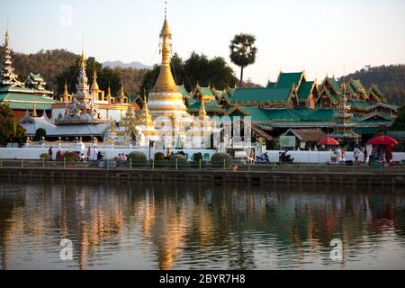 Les habitants de la région apprécient le coucher du soleil sur le lac Nong Chong Kham à Mae Hong son, en Thaïlande, avec les temples Wat Chong Klang et Wat Chong Kham en arrière-plan. Banque D'Images