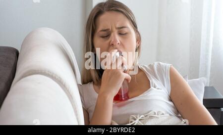 Jeune femme malade avec mal de gorge en utilisant un spray de gorge Banque D'Images
