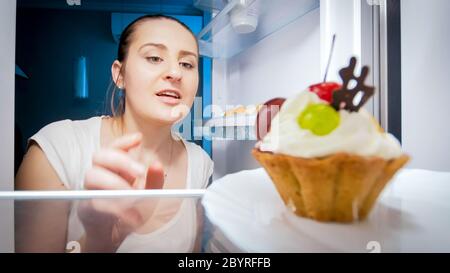 Femme affamée à la recherche de quelque chose à manger dans la cuisine la nuit. Concept de régime alimentaire et de nutrition saine Banque D'Images