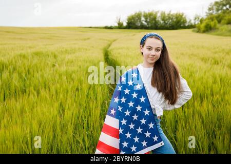 Jolie jeune fille pré-ado dans le champ tenant le drapeau américain. Banque D'Images