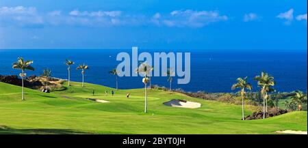 Panorama des golfeurs sur le green du parcours de montagne de Kona Country Club (propriété libérée) à Kailua Kona, Hawaï avec l'océan Pacifique à distance. Banque D'Images
