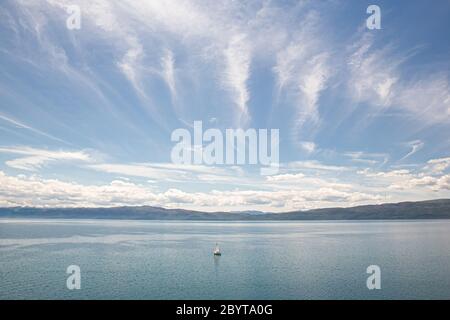 Vue panoramique d'un bateau naviguant seul sur le lac d'Ohrid par une belle journée d'été, ville d'Ohrid, République de Macédoine du Nord (ARYM) Banque D'Images