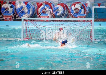 Un joueur de water-polo dans une piscine qui a été un but de projection d'eau Banque D'Images