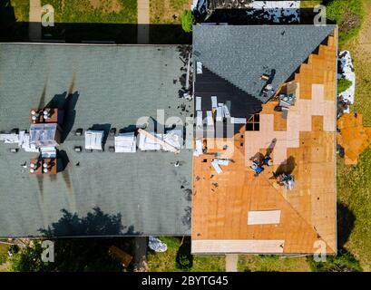 Vue aérienne du réparateur de construction de toit sur un appartement résidentiel avec nouveau bardeau de toit en cours d'application Banque D'Images