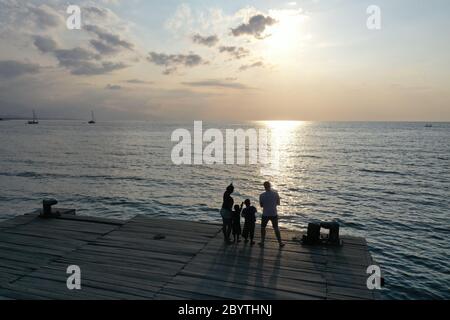 La famille regarde le coucher du soleil sur la plage de Lovina Bali Indonésie Banque D'Images