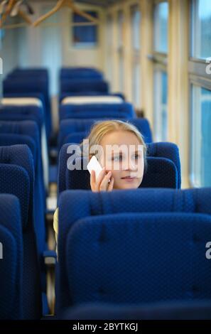 Femme assise dans un train de parler sur son mobile Banque D'Images