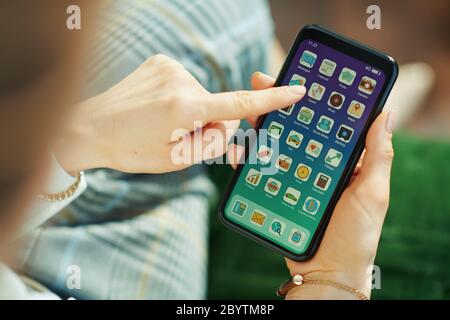 Gros plan sur une femme dans le salon en journée ensoleillée ouvrant l'application de santé sur un smartphone. Banque D'Images