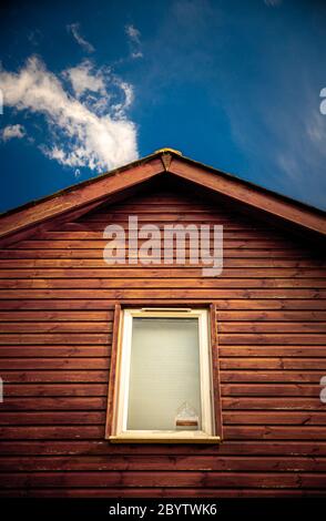 cabane en bois avec fenêtre et toit contre ciel bleu et nuages Banque D'Images