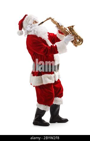 Photo de profil pleine longueur du Père Noël debout et jouant au sax isolé sur fond blanc Banque D'Images