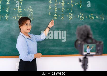 Professeur asiatique principal enseignant expliquant les mathématiques dans le tableau noir donner à distance classe enseignement en ligne de cours regardant la caméra dans la salle de classe par e-learni Banque D'Images