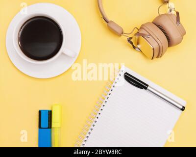 Planificateur plat photo avec espace de copie Notebook, marqueurs colorés, casque et tasse de café noir sur fond jaune Banque D'Images