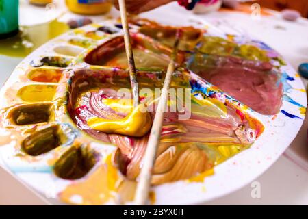 Une fille utilise une peinture acrylique brosse pour faire ses dessins sur toile. Banque D'Images