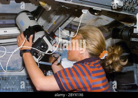 (12 août 1997) --- l'astronaute N. Jan Davis, commandant de charge utile, utilise une caméra d'observation de la Terre de grand format à travers la fenêtre au-dessus du pont arrière de la navette spatiale Discovery. Banque D'Images