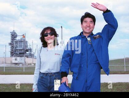 Takao Doi, spécialiste de mission STS-87, de l'Agence nationale de développement spatial du Japon, pose avec son épouse, Hitomi Doi, devant le panneau de lancement 39B du Centre spatial Kennedy, au cours des dernières activités de prélancement qui ont précédé le décollage prévu du 19 novembre. Les autres membres de l'équipage du STS-87 sont le commandant Kevin Kregel; le pilote Steven Lindsey; les spécialistes de mission Kalpana Chawla, Ph.D., et Winston Scott; et le spécialiste de la charge utile Leonid Kadenyuk, de l'Agence spatiale nationale d'Ukraine. STS-87 sera le quatrième vol de la charge utile de microgravité des États-Unis et du satellite déployable Spartan-201 Banque D'Images