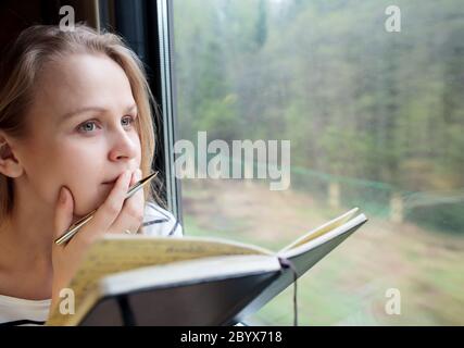 Jeune femme dans un train à écrire des notes Banque D'Images