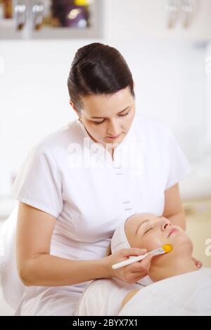 Cosmetician appliquant un masque à l'aide de brush Banque D'Images