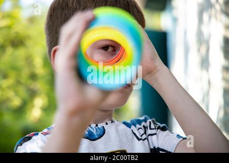 Jeune garçon regardant à travers un jouet coloré comme un télescope. Banque D'Images