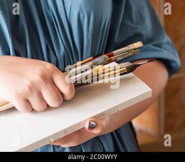 Une femme tient des brosses dans ses mains pour dessiner avec des aquarelles. Concept d'art de loisir. Mise au point sélective en gros plan. Banque D'Images