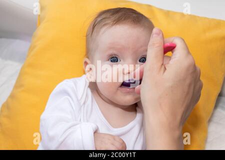 Petite fille mignonne couché sur le lit et mangeant de la soupe de riz avec une cuillère. Mère qui nourrit sa petite fille. La petite fille a quatre mois. Banque D'Images