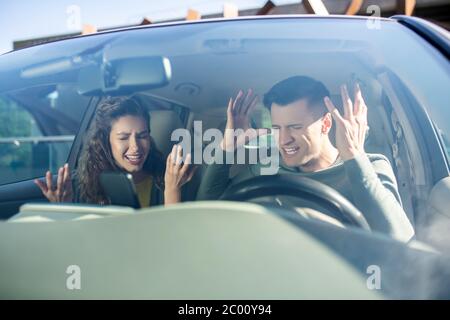 Homme et femme qui se juque dans une voiture Banque D'Images