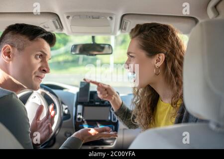 Un jeune homme et une jeune femme en conflit dans un salon de voiture Banque D'Images