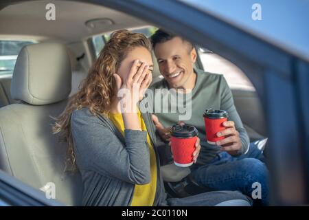 Homme et femme avec des lunettes en plastique dans les mains en voiture Banque D'Images