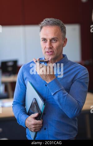 Homme caucasien tenant des dossiers et parlant au téléphone Banque D'Images