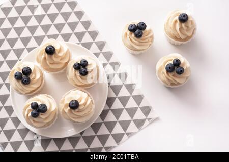Petits gâteaux faits maison avec myrtille et crème vanille sur assiette en porcelaine. Style de pose à plat. Copier l'espace. Banque D'Images