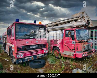 Deux moteurs d'incendie abandonnés, rouillés et abandonnés avec peinture décoloration, l'un Dennis et l'autre Dodge, laissés dans un complexe de stockage clos. Banque D'Images