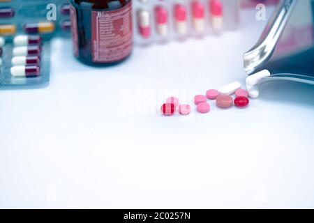 Comprimés rouges, roses et blancs comprimés avec plateau de médicaments sur flacon de médicament en verre flou et blister. Comprimés craquelés pilules. Médicaments périmés. Médicament analgésique. Banque D'Images