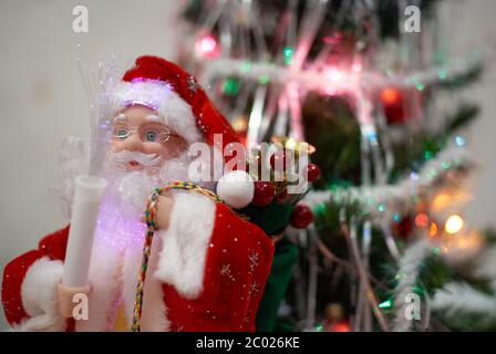 Poupée du Père Noël avec cadeaux devant un arbre de Noël flou sur le fond Banque D'Images