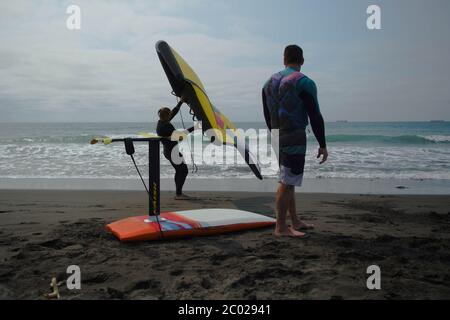 Un homme se tient sur une plage pratiquant avec une aile à main pour le surf d'aile hydrofoil. Banque D'Images