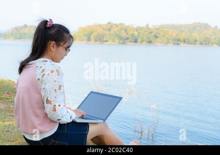 Jeune fille avec ordinateur portable assise sur la rive Banque D'Images