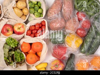 Zéro déchet par rapport aux emballages en plastique. Fruits et légumes dans des sacs en coton réutilisables écologiques et dans des sacs en plastique, vue du dessus Banque D'Images