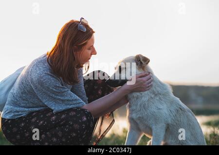 Femme et chien dans la nature au coucher du soleil. Relations, communication et interaction entre les humains et les animaux de compagnie Banque D'Images