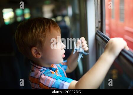 Petit garçon avec toy regardant par la fenêtre du train Banque D'Images