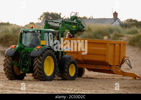 Tracteur ramassant les poubelles sur la plage et les déversant dans un saut industriel pour élimination, Hunstanton, Norfolk, Angleterre Banque D'Images