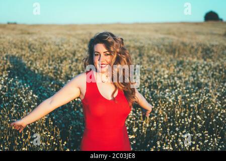 femme en robe rouge appréciant la liberté dans un domaine de pâquerettes Banque D'Images