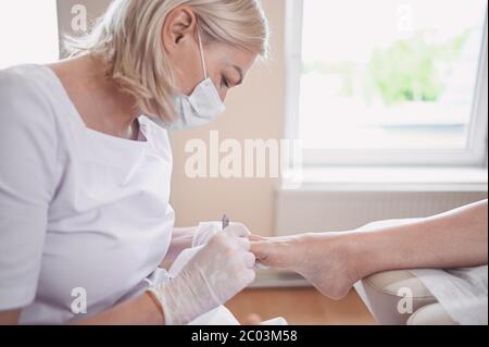 Procédure médicale professionnelle de pédicure gros plan à l'aide d'un coupe-ongles. Patient visitant le podiatre chiropodiste. Soins des pieds dans le salon DE SPA. Banque D'Images