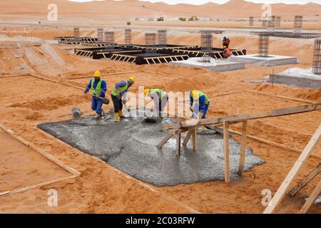 Verser du béton dans des coffrages pour construire des fondations pour une grande installation pétrolière dans le désert du Sahara. Banque D'Images