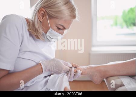 Procédure médicale professionnelle de pédicure gros plan à l'aide d'un coupe-ongles. Patient visitant le podiatre chiropodiste. Soins des pieds dans le salon DE SPA. Banque D'Images