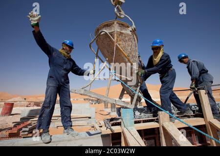 Verser du béton dans des coffrages pour construire des fondations pour une grande installation pétrolière dans le désert du Sahara. Banque D'Images