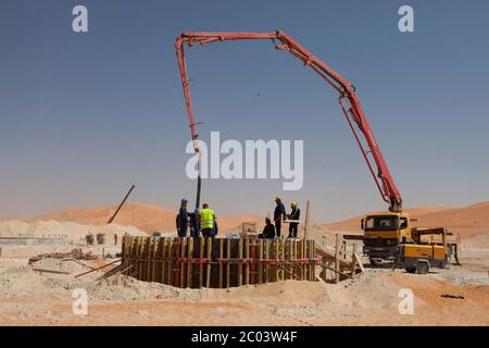 Verser du béton dans des coffrages pour construire des fondations pour une grande installation pétrolière dans le désert du Sahara. Banque D'Images