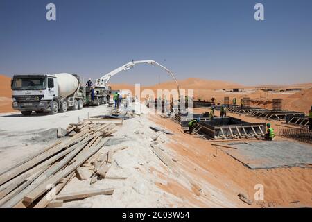 Verser du béton dans des coffrages pour construire des fondations pour une grande installation pétrolière dans le désert du Sahara. Banque D'Images