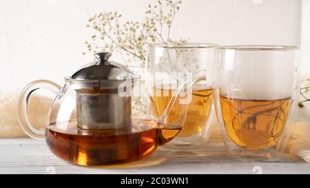 Thé romantique le matin pour les couples. Thé noir dans une théière en verre ordinaire. Thé chaud dans les tasses à double paroi. Mugs à double paroi. Banque D'Images