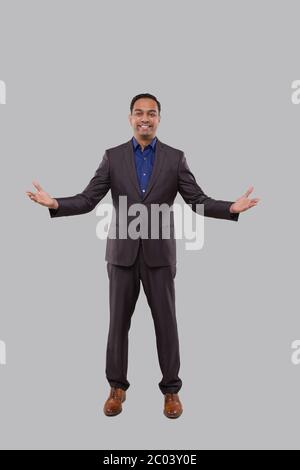 Homme d'affaires mains à côtés Bienvenue geste isolé. Homme d'affaires indien debout pleine longueur Banque D'Images