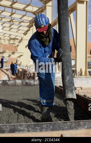 Verser du béton dans des coffrages pour construire des fondations pour une grande installation pétrolière dans le désert du Sahara. Banque D'Images